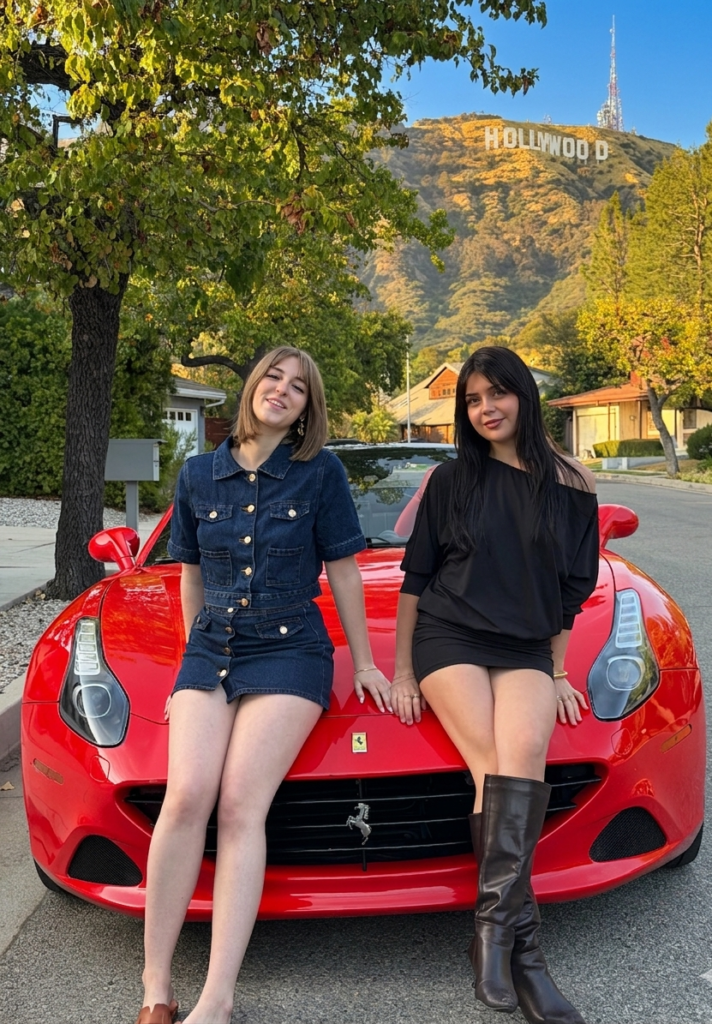 Two friends posing in front of a red Ferrari near the Hollywood Sign during a graduation celebration experience in Los Angeles.