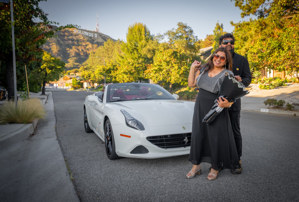 Couple celebrating with a white Ferrari California T and the Hollywood Sign in the background during a romantic Ferrari driving experience in Los Angeles.
