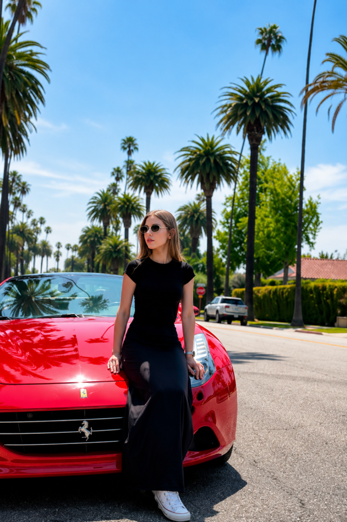 Woman posing beside a red Ferrari on a palm-lined street in Los Angeles