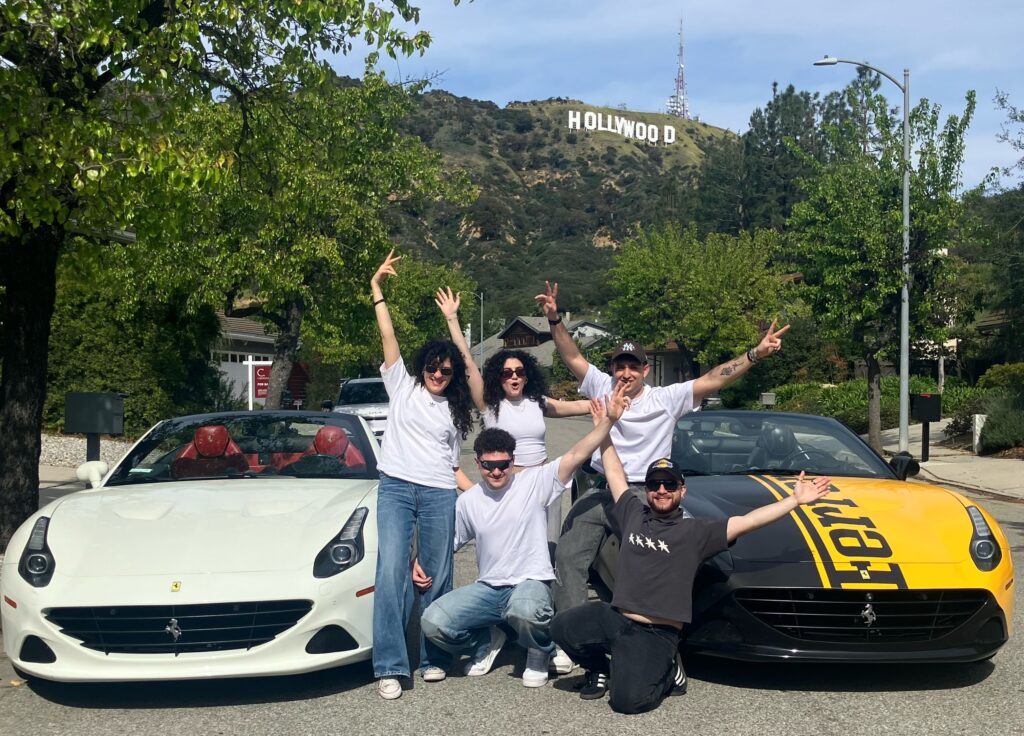 Group posing with two Ferrari California T cars near the Hollywood Sign in Los Angeles