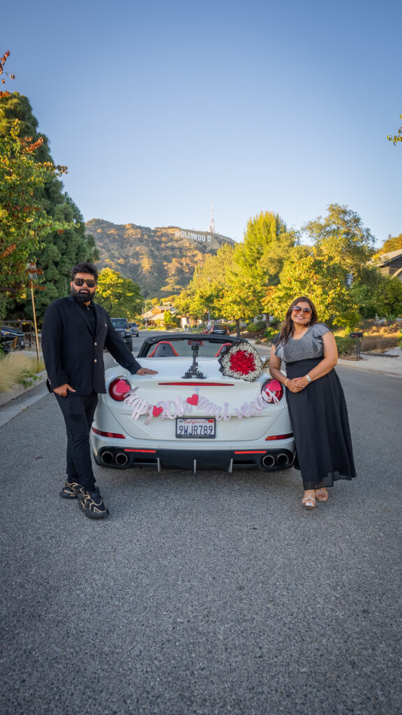 couple celebrating 20th anniversary in LA with white ferrari at hollywood sign photo stop