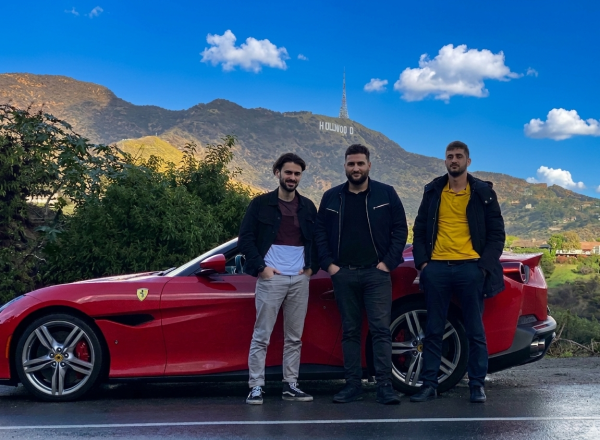 Friends posing with a red Ferrari near the Hollywood Sign, one of the most memorable things to do in Los Angeles.