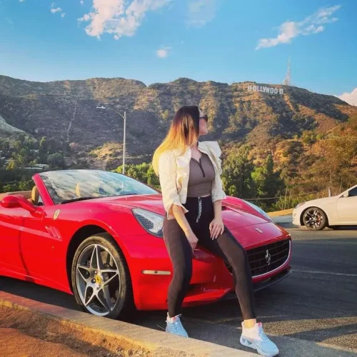woman in front of a ferrari with hollywood sign